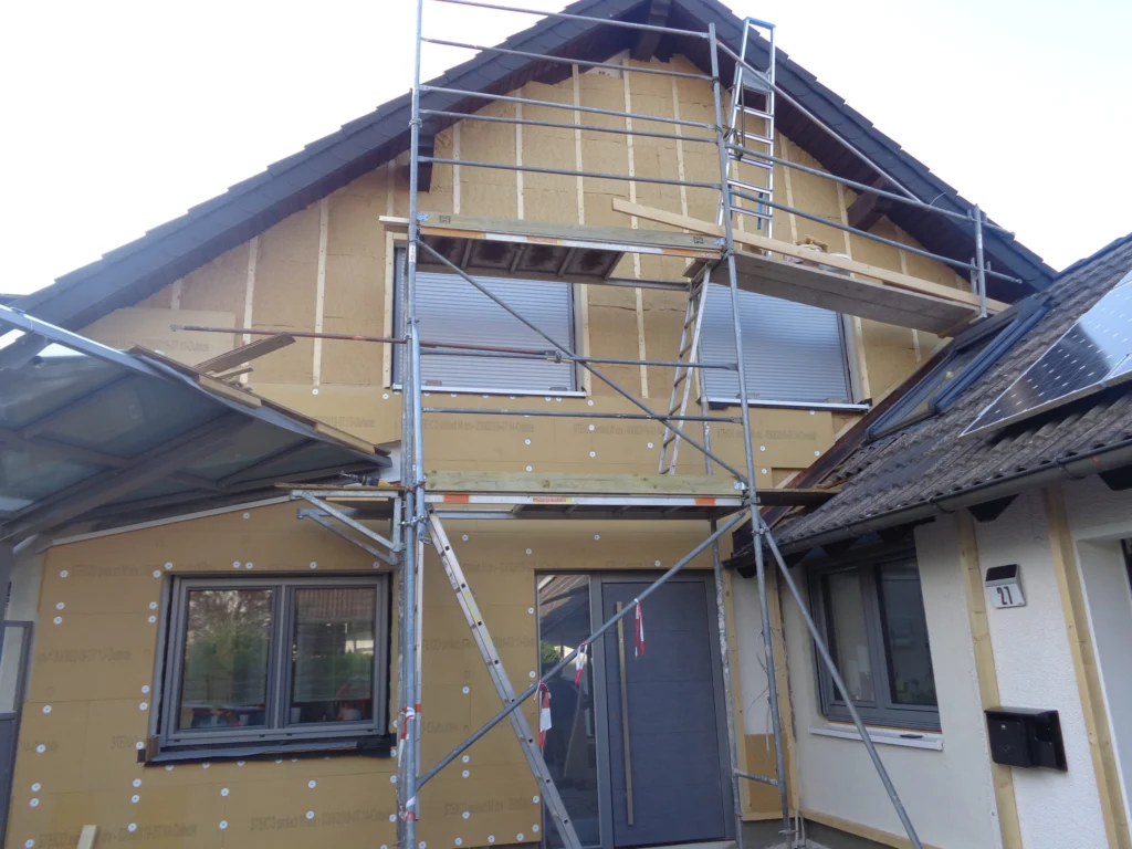Wohnhaus während der energetischen Sanierung mit montierter Außenwanddämmung und Gerüst