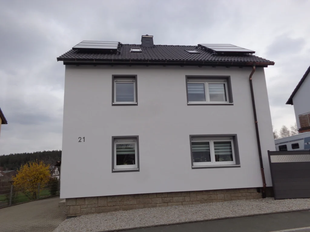 Energetisch modernisiertes Einfamilienhaus mit gedämmter Fassade, neuen Fenstern und Photovoltaikanlage auf dem Dach